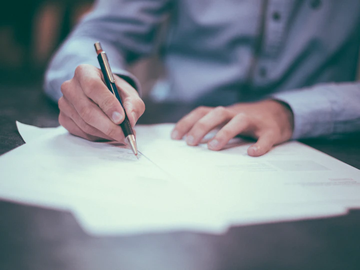 Persona firmando un documento sobre un escritorio